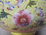 un vase jaune orné de fleurs, posé sur une table