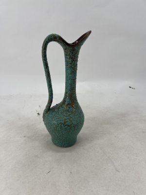 a green vase that is sitting on a white surface