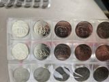 many different coins in a plastic container on a table