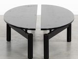 a black coffee table with two black legs on a concrete floor