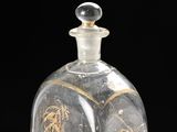 a glass bottle with a gold design on it