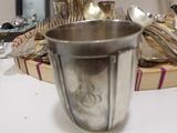 a silver cup sitting on a table next to a basket of silverware