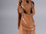 une photo représentant une statue en bois d'une femme tenant un sac