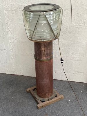 une lampe posée sur un socle en bois près d'un mur blanc