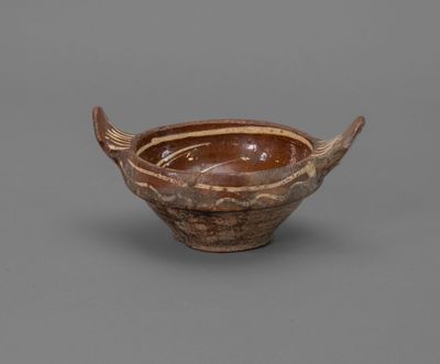 a brown and white bowl sitting on top of a gray surface