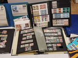 beaucoup de timbres posés sur une table, à côté d'un classeur