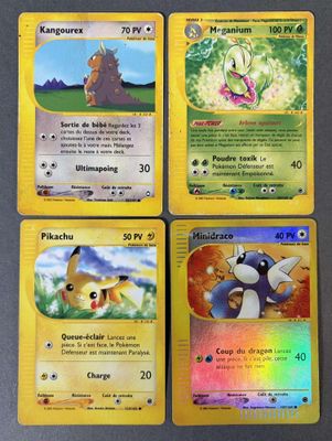 quatre cartes Pokémon empilées les unes sur les autres sur une table