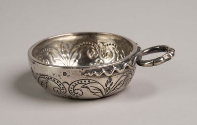 un petit bol en argent avec une anse sur une table