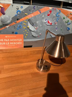 a lamp that is sitting on a table in front of a climbing wall