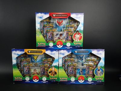 trois boîtes de figurines Pokémon posées sur une surface noire