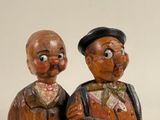 two wooden figurines of two men sitting on a table