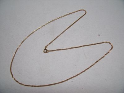 a close up of a gold chain on a white surface
