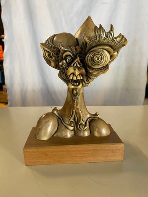 une statue en bronze représentant une créature, posée sur un socle en bois