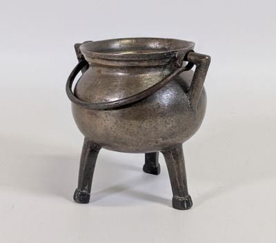 une vieille casserole en métal posée sur un support en bois