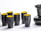 neuf tasses et un pichet posés les uns à côté des autres sur une table