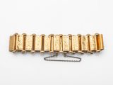 gros plan d'un bracelet en or sur une surface blanche