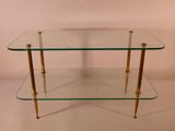 une table basse en verre et en laiton avec deux étagères