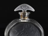 a clear glass perfume bottle sitting on top of a black surface