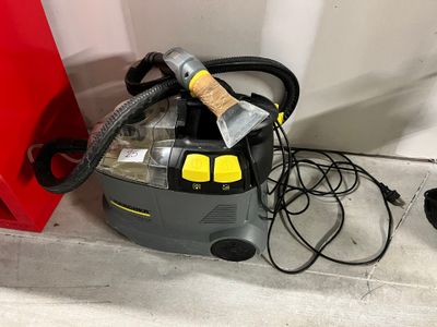 un aspirateur posé par terre à côté d'une porte rouge
