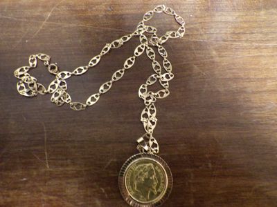 un collier auquel est accrochée une pièce, posé sur une table