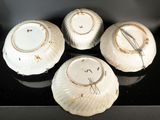 four white and gold plates sitting on top of a black counter
