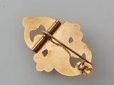 a gold brooch on a table with a white background