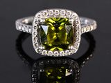 a close up of a green and white diamond ring on a black surface
