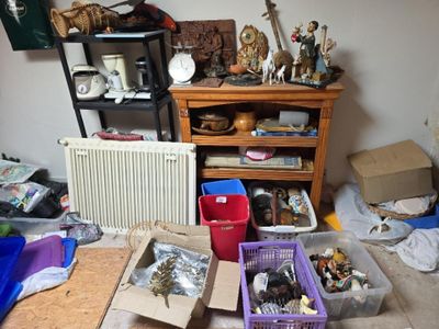 Des cartons contenant des objets divers sont posés par terre dans une pièce encombrée.
