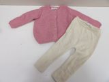 a pink sweater and beige pants on a white table