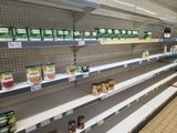 many empty shelves in a grocery store with canned food on them