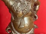 bronze statue of a man holding a pot on a red surface