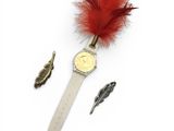 a watch with a feather on it next to other items