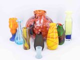 many different colored vases sitting on a white surface