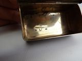 someone is holding a silver box with a silver lid on a table