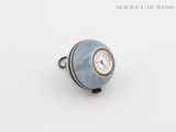 un anneau renfermant une horloge, posé sur une surface blanche