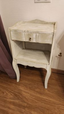 a white table with a drawer on it in the corner of a room