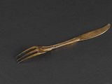 a close up of a gold fork on a black surface