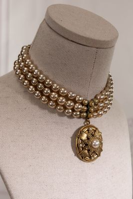 pearl and gold necklace with a medallion pendant on a mannequin