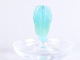 un bougeoir en verre contenant une bougie verte