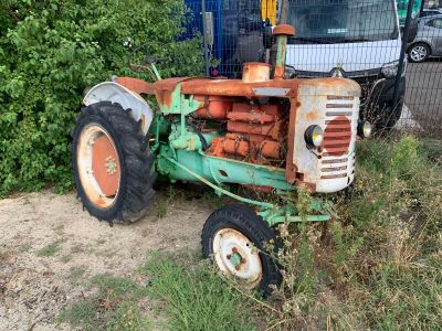 un tracteur qui est garé dans l'herbe près d'une clôture