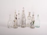 de nombreuses bouteilles en verre alignées sur une surface blanche