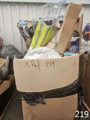 une boîte en carton sur laquelle est accrochée une pancarte, posée au milieu d'une pile d'autres boîtes