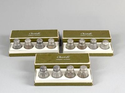 four silver salt and pepper shakers in a box on a white surface
