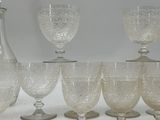 seven wine glasses and a decanter sitting on a table