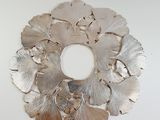 a metal wreath made of silver leaves on a white surface