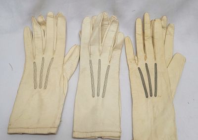three pairs of white leather gloves sitting on top of a white table