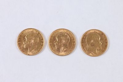 trois pièces d'or sont alignées sur une surface blanche