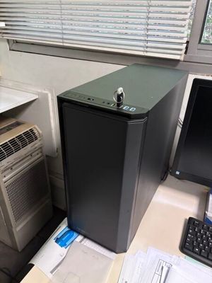 un petit ordinateur noir posé sur un bureau, à côté d'un écran d'ordinateur