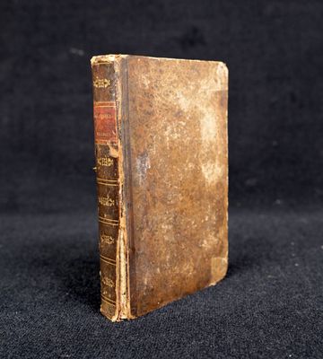 un vieux livre posé sur une table recouverte d'un tissu noir