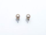 une paire de boucles d'oreilles en perles et diamants posées sur une surface blanche